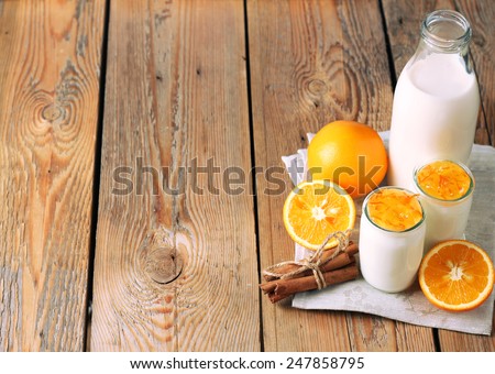 Breakfast products (homemade yogurt, orange and cinnamon jam, milk) on a wooden table. Selective focus, copy space background