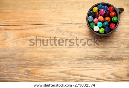 Still life, business, education concept. Crayons in a mug on a wooden table. Selective focus, top view, copy space background