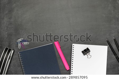 Still life, business, education concept. Office supplies, notepad, diary, marker, stapler, pens and pencils on a chalkboard. Selective focus, copy space background, top view
