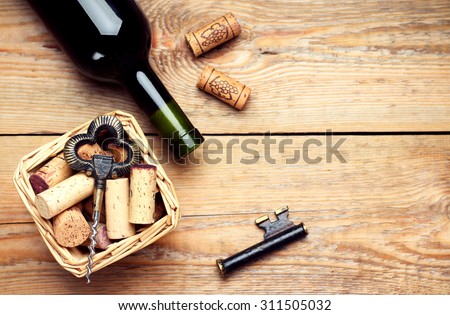 Still life, food and drink, holidays concept. Basket with wine corks, bottle and corkscrew on a wooden table. Selective focus, copy space background, top view