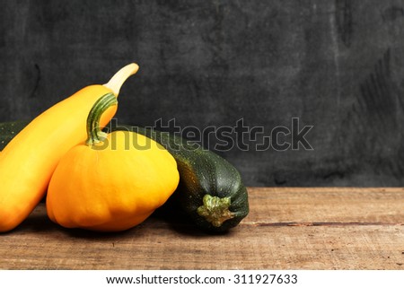 Still life, food and drink, holidays, halloween concept. Pumpkin and zucchini on a wooden table. Selective focus, copy space chalkboard