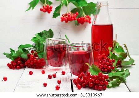 Still life, food and drink, health and homeopathy concept. Viburnum (guelder rose) drink in glass on a wooden table. Selective focus