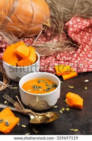 Still life, food and drink, seasonal concept. Fresh orange pumpkin soup in a bowl on a black rustic table. Selective focus