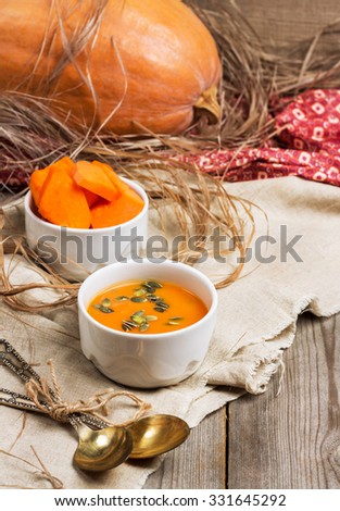 Still life, food and drink, seasonal concept. Fresh orange pumpkin soup in a bowl on a rustic wooden table. Selective focus
