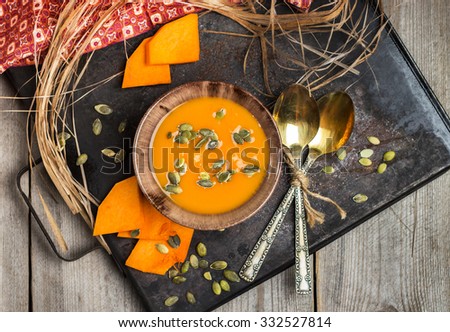 Still life, food and drink, seasonal concept. Fresh orange pumpkin soup in a bowl on a rustic table. Selective focus, top view