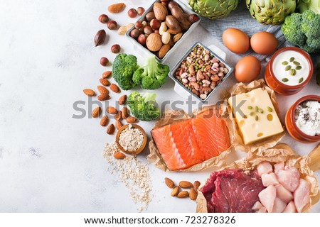 Assortment of healthy protein source and body building food. Meat beef salmon chicken breast eggs dairy products cheese yogurt beans artichokes broccoli nuts oat meal. Copy space background, top view