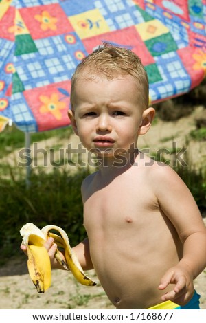 Small boy over the lake during the rest eat banana