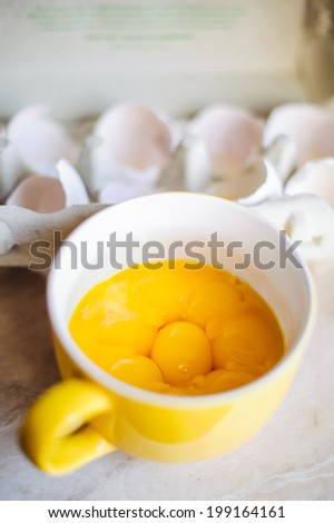 Cup of egg yolks on the kitchen background dozen of egg shells