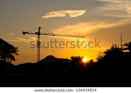 Industrial landscape. Construction cranes and concrete structure at silhouettes sunset.