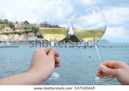 Two wineglasses in the hands against the harbour of Portvenere, Italy