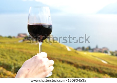 Glass of wine in the hand against vineyards in Lavaux region, Switzerland
