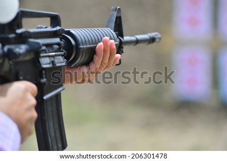 Man aiming at a target and shooting an automatic rifle for
