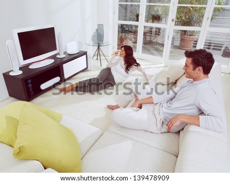 Happy Mature Couple Sitting On Couch And Watching Television Together