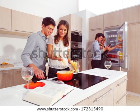 Group Of Young Friends Preparing Breakfast In Modern Kitchen