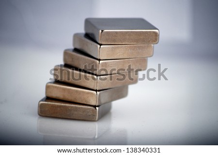 A stack of nickel plated rare earth magnets off on a reflective white translucent surface