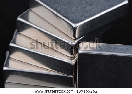 Stacked nickel plated neodymium iron boron rare earth magnets on a black background