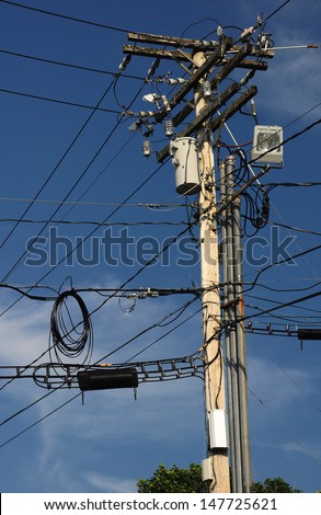 A utility pole with many wires and items using the pole