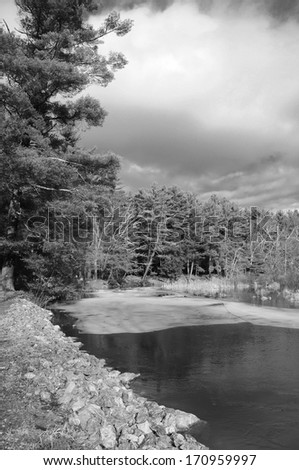 A black and white image of ice on the Bantam River flowing through White Memorial located in Litchfield Connecticut on a sunny winter day.