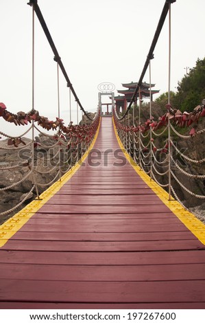 A suspension bridge with heart or love lockets locked to the chain railings in Yantai China.