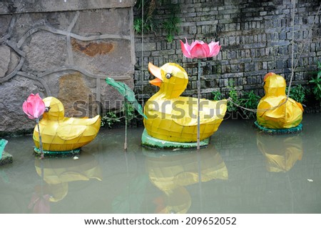 Floating yellow ducks and lotus flowers in a water canal in Xinchang Ancient town in Pudong area of Shanghai China.