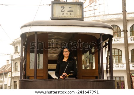 An asian woman tourist standing on an old style trolley car for Line 2 in Shanghai film park.