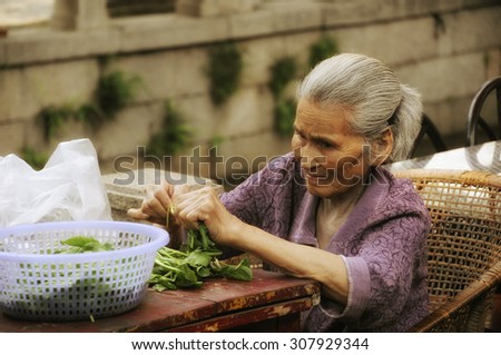 August 20, 2015, Tongli Town, China. An elderly chinese woman sitting at a table tearing spinach leaves into smaller pieces at Tongli town Jiangsu province China.