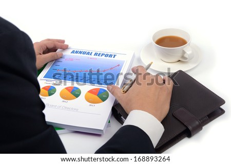 Over the shoulder view image of chief executives officer is reading the annual report of the company.