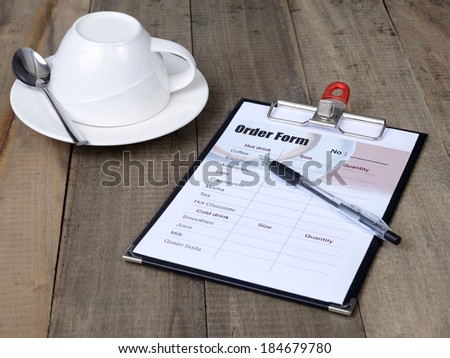 Empty cup of coffee and order form lay on wooden table.