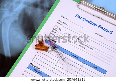 Pet medical record on clipboard and bottle of vaccine with syringe.