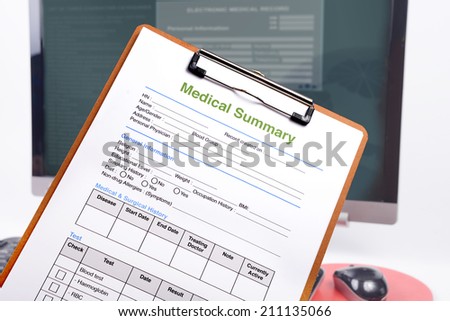 Medical summary on clipboard in front of computer.