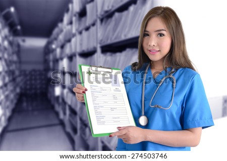 Female doctor in blue uniform holding medical record in hands in front of blue background of medical record archives.