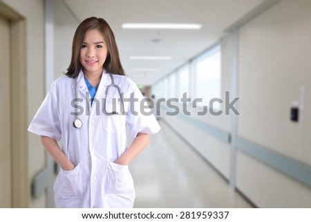 Nice and hospitality female doctor standing with hospital walkway on background.