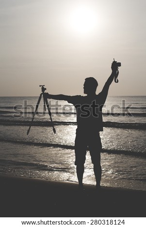 Silhouette of people on a beach. Man holding photography equipment on the beach.