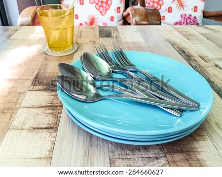 Spoon and empty plate on the table.spoon and fork on a plate on the wood table