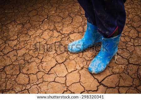 Feet in boots on a cracked soil in dry season