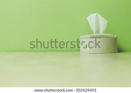 white plastic tissue box on green background.
