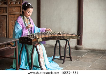 Suzhou, China - APRIL 9: A woman dressed in ancient chinese clothing playing the guzheng. April 9, 2011 in Suzhou City, Jiangsu Province, China.