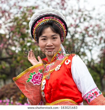DALI, CHINA - MARCH 20, 2014: A woman dressed in ancient Bai nationality clothing, smiling and welcome the travelers from all over the world. Located in Dali Ancient City, Yunnan Province, China.