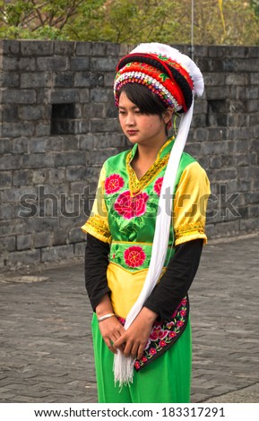 DALI, CHINA - MARCH 20, 2014: A woman dressed in ancient Bai nationality clothing looking downwards,on the south gate tower of Dali ancient city. Located in Dali City, Yunnan Province, China.