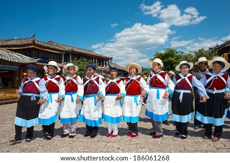 LIJIANG, CHINA - APRIL 7, 2014:  A group of Naxi nationality old women dressed in national clothing dancing. Located in Lijiang Old Town Square Street (Sifang Street), Yunnan Province, China.