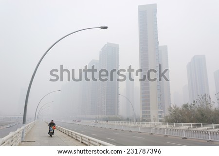 SHENYANG, CHINA - OCTOBER 31, 2014: City in a heavy hazy weather, people are riding electric bicycle. Located in Sanhao Bridge, Shenyang City, Liaoning Province, China.