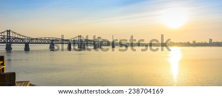 Yalu River Bridge and Yalu River at morning. In the distance is North Korea. Located in Dandong City, Liaoning province, China.
