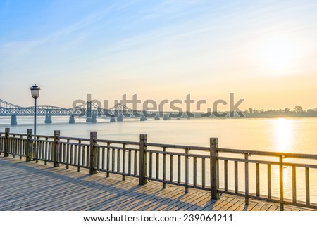 Yalu River Bridge at morning. In the distance is North Korea. Located in Yalu River Scenic Areas of Dandong City, Liaoning province, China.