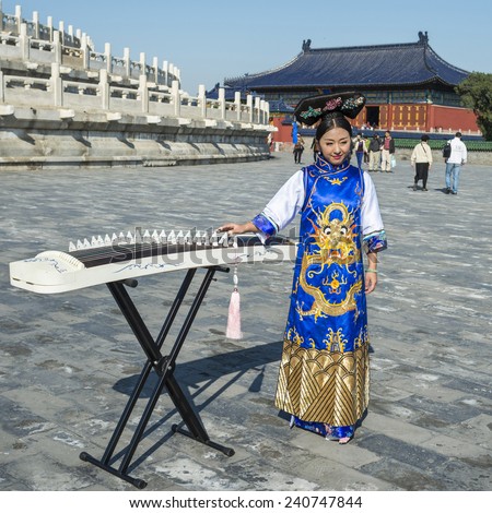 Beijing, China - October 14, 2014: A woman dressed in ancient chinese clothing and the traditional chinese instrument guzheng. Located in The Temple of Heaven, Beijing, China.