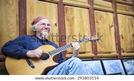Lijiang, China - March 30, 2014: An old man playing the guitar. Located in Old Town of Lijiang, Yunnan Province, China.