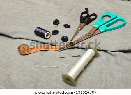 Tools for cutting and sewing lie on the fabric. Scissors, buttons and thread.