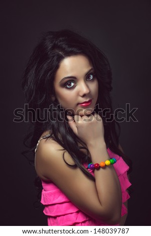 Thoughtful girl with big expressive eyes and a slight smile. Portrait of a young beautiful girl on a dark background.