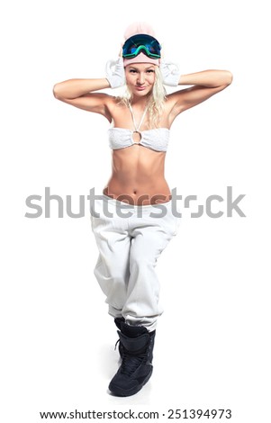 Posing girl in white pants, bra, snowboarding hat, boots and mask on a light background.