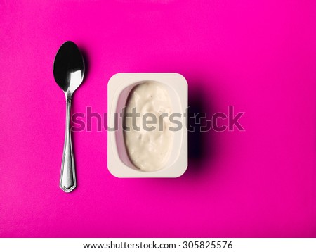 Opened packages of yogurt on a bright colored background close-up. Packaging of yogurt and a teaspoon.