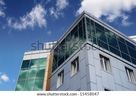 Modern building on blue sky background with reflection of the sky on windows